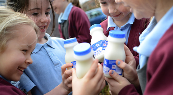 School children holding creamline milk bottles